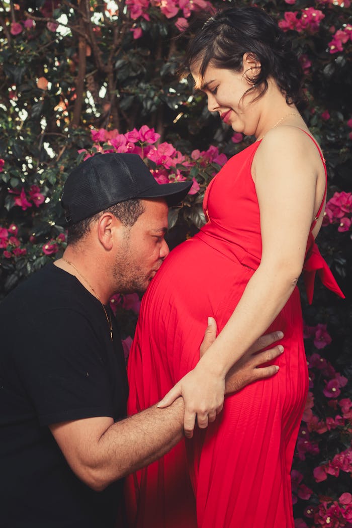 A loving couple embracing a pregnant belly in a garden of vibrant flowers.